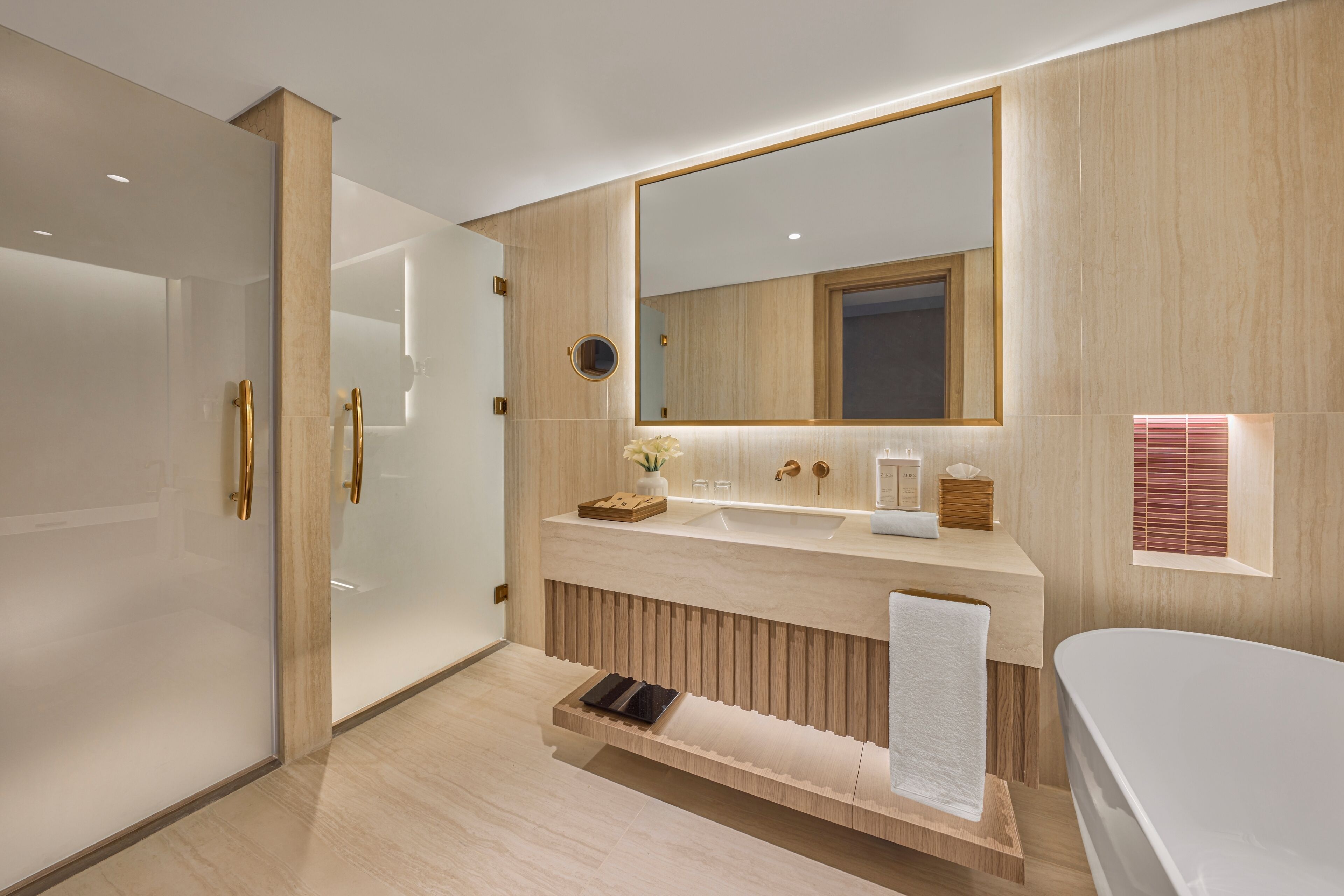 A modern bathroom with a large mirror, a bathtub, and a vanity with a towel rack.