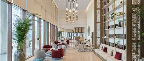 A spacious lobby with a high ceiling, modern furniture, and a large chandelier.