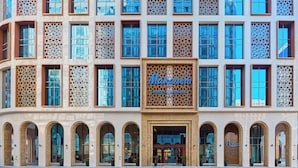 A modern building with a large sign reading "Makarem." It features multiple windows with intricate designs and a series of arched doorways.