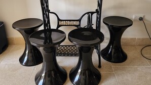 Une table dont le plateau est en bois et les pieds en métal noir, entourée de quatre tabourets noirs à la finition brillante.