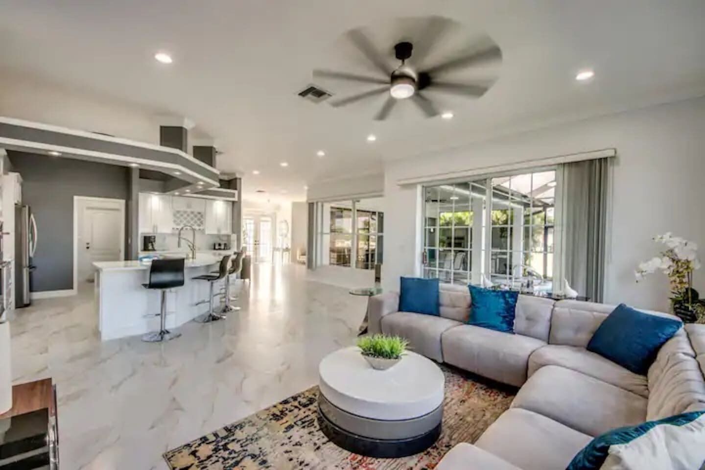 A modern living room with a large sofa, a coffee table, and a ceiling fan.