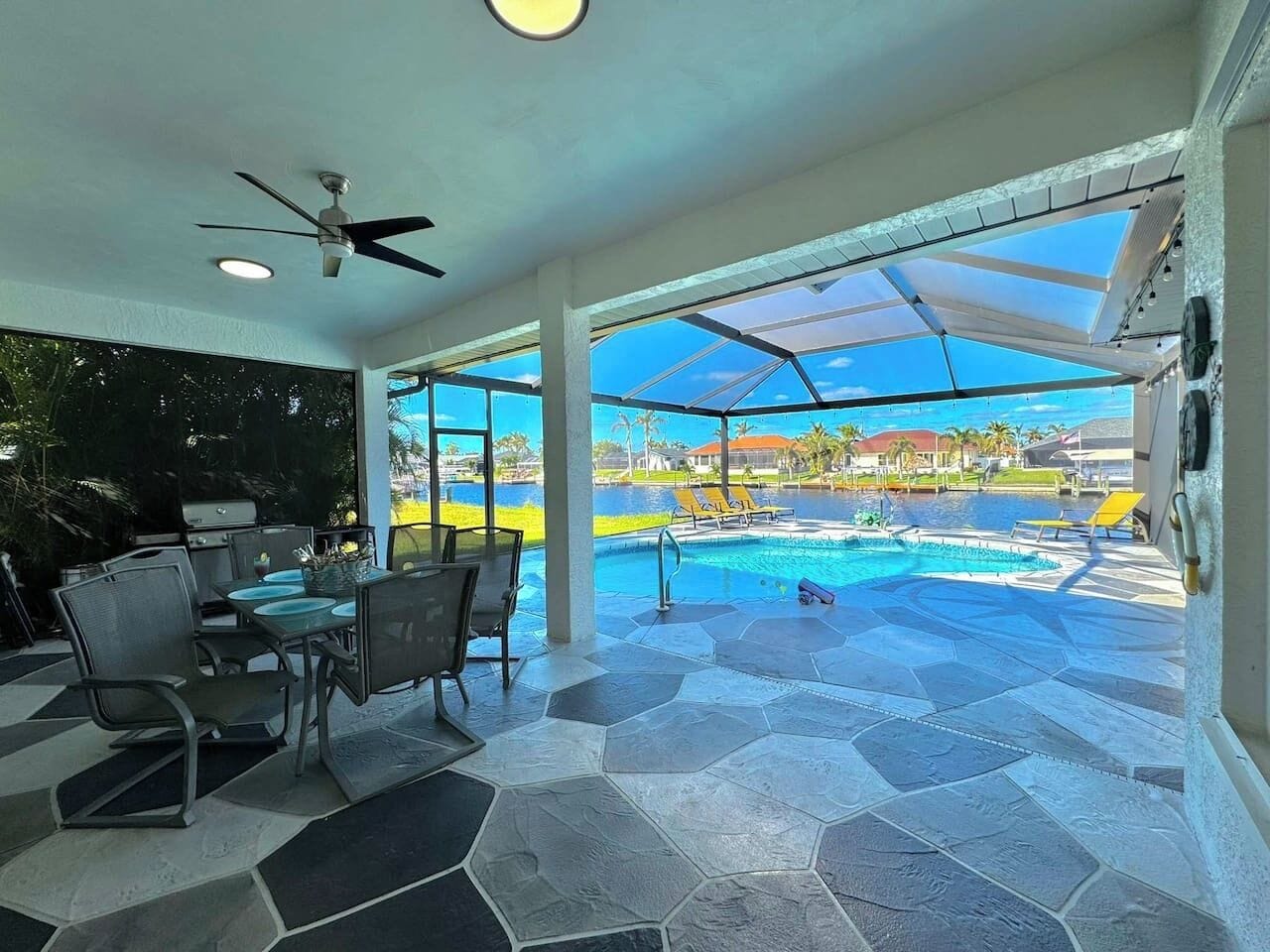 Un espace extérieur abrité comprenant une piscine, du mobilier de jardin et une vue sur un complexe hôtelier.