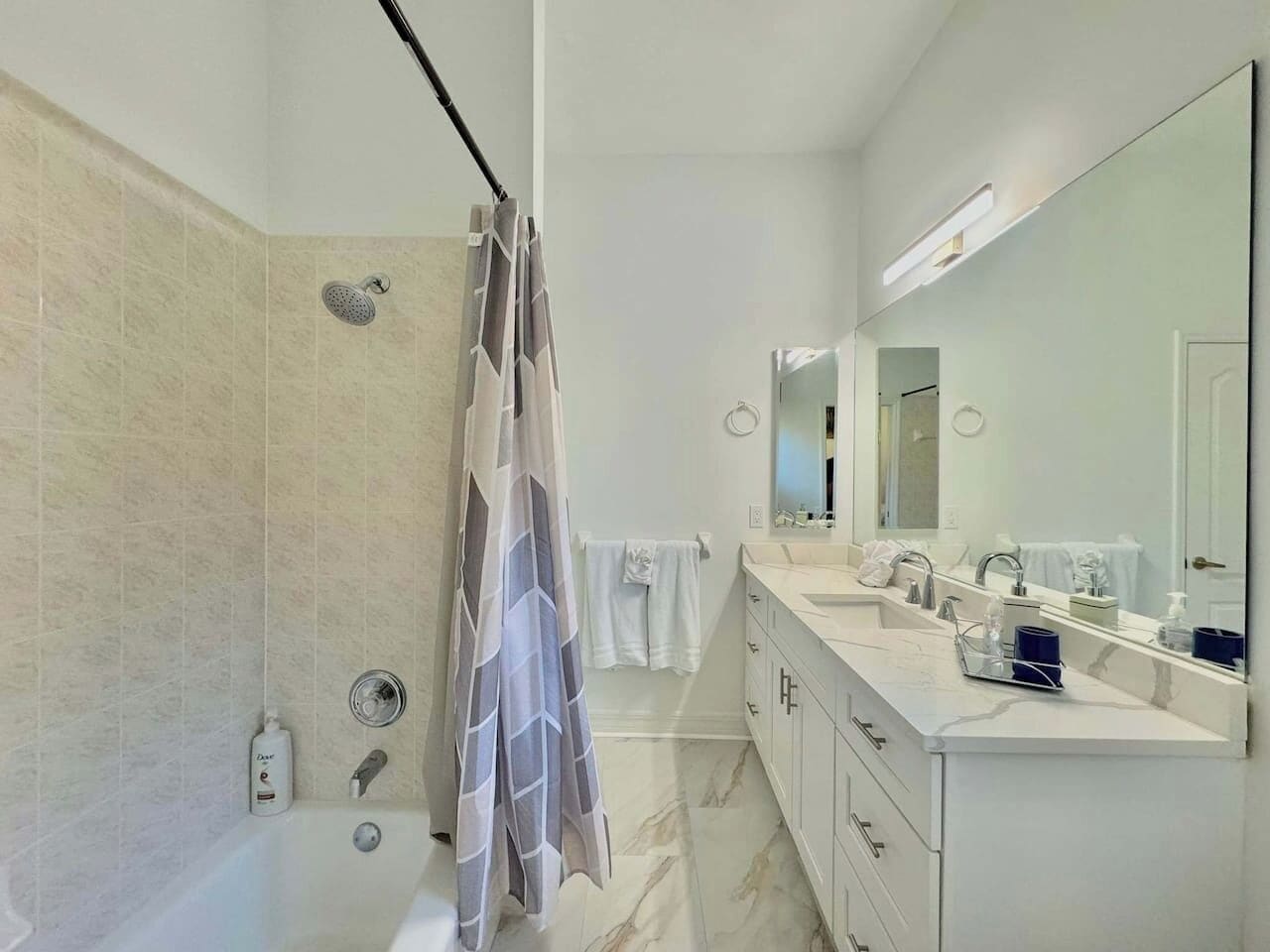 Un bagno moderno con doccia, vasca, mobile lavabo con specchio e porta asciugamani.