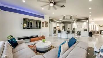 A modern living room with a sofa set, a coffee table, and a dining area with bar stools.