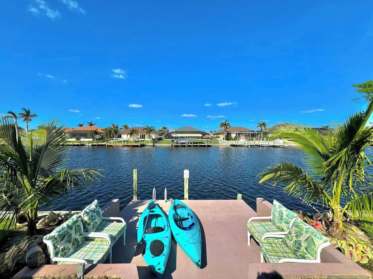 Un muelle frente al agua con kayaks y sillas de descanso.