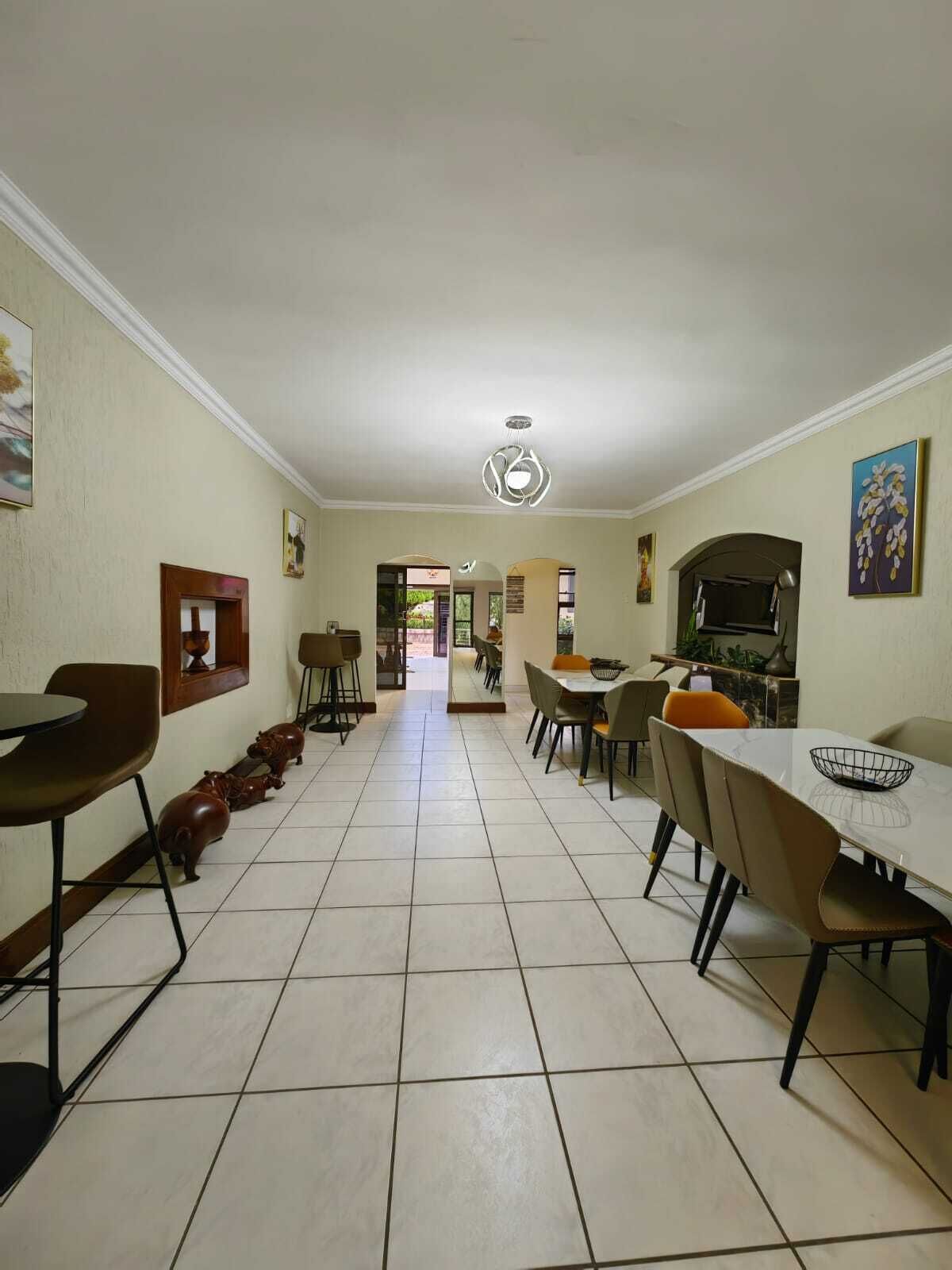 Un comedor amplio con una mesa larga y sillas, piso de baldosas y vista a otra habitación.