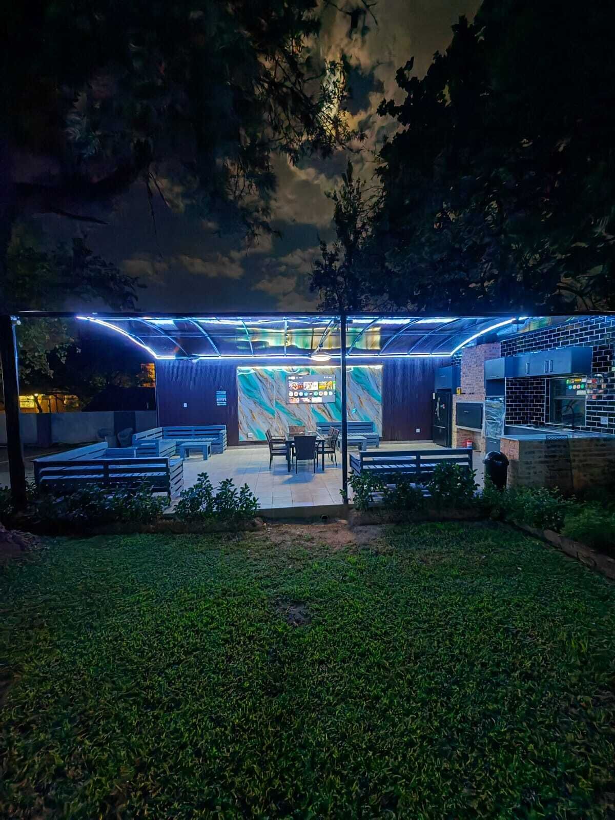 Un espacio al aire libre con una zona de estar cubierta, una pantalla digital y una estructura de ladrillo.
