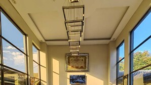 Un hall d’entrée spacieux, doté de grandes fenêtres, d’une table basse en verre au centre et d’un canapé en cuir.