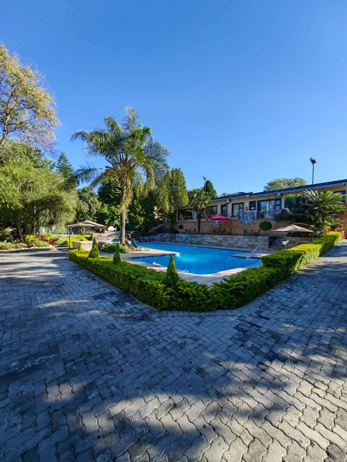 Una piscina rodeada por un jardín ajardinado con un sendero pavimentado.