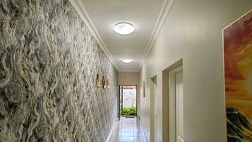 A hallway with a textured wall, recessed ceiling lights, and a door at the end.