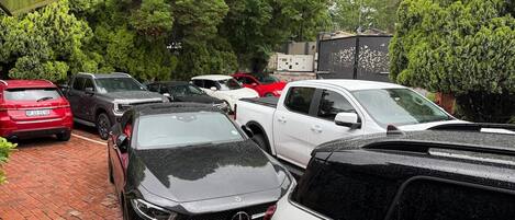 Un espace de stationnement où sont garées plusieurs voitures, dont une Mercedes-Benz noire et un VUS blanc.