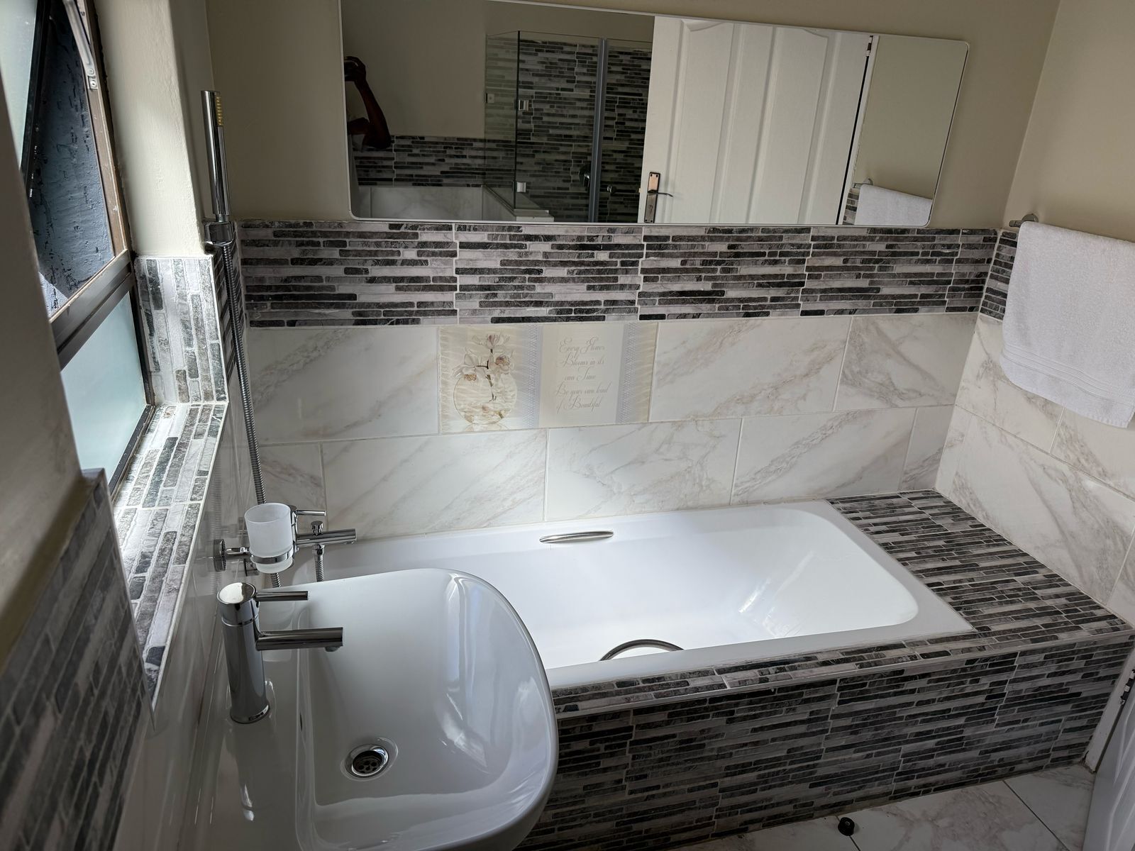 A modern bathroom with a large bathtub, a sink, and a mirror.