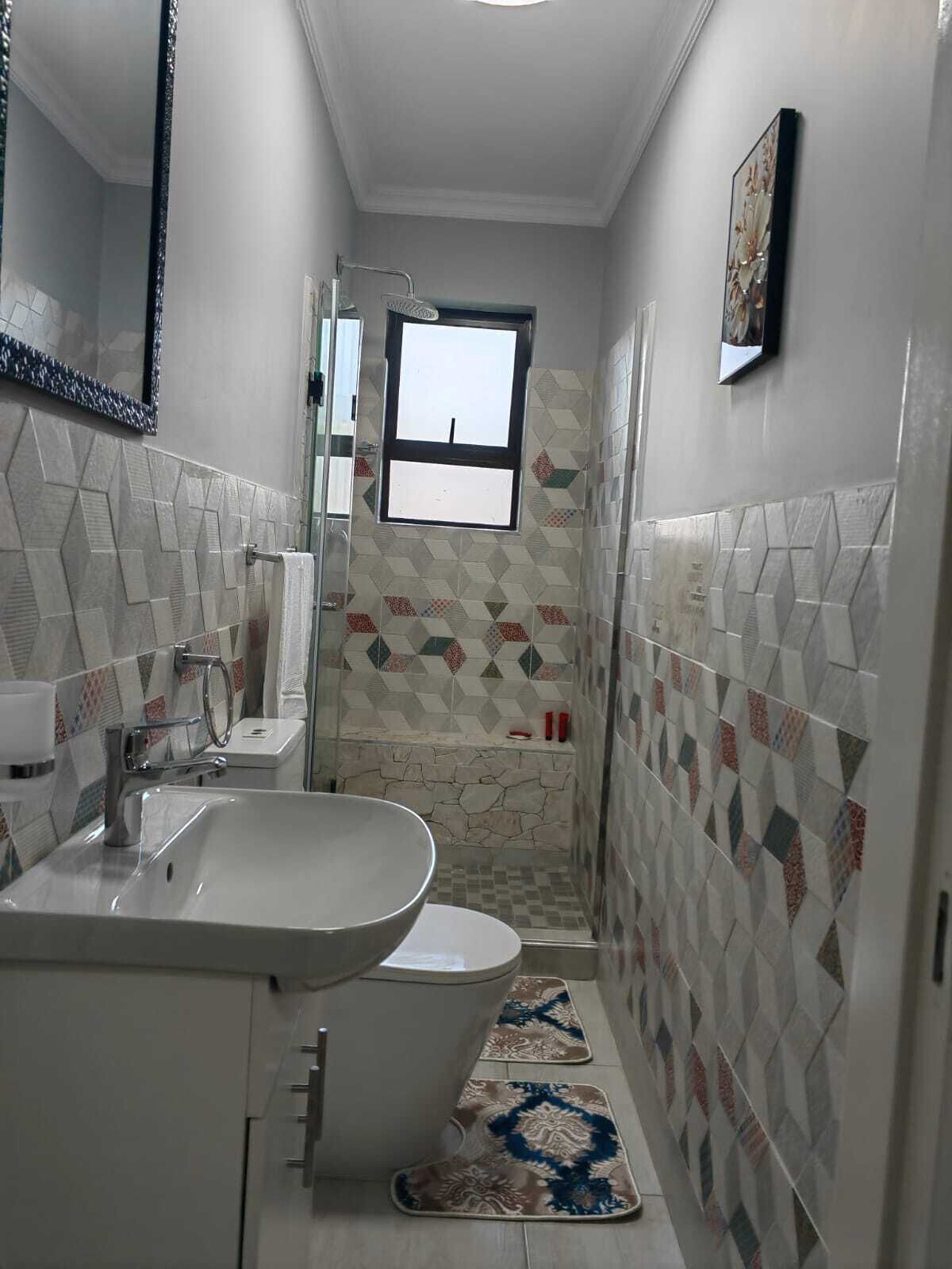Casa de banho pequena com lavatório, sanita e zona de duche.