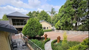 Une cour avec un espace patio, un chemin et un petit bâtiment.