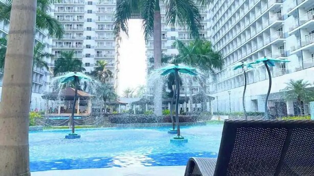 A swimming pool area with palm trees and a bench. - House of Wu (Pasay)