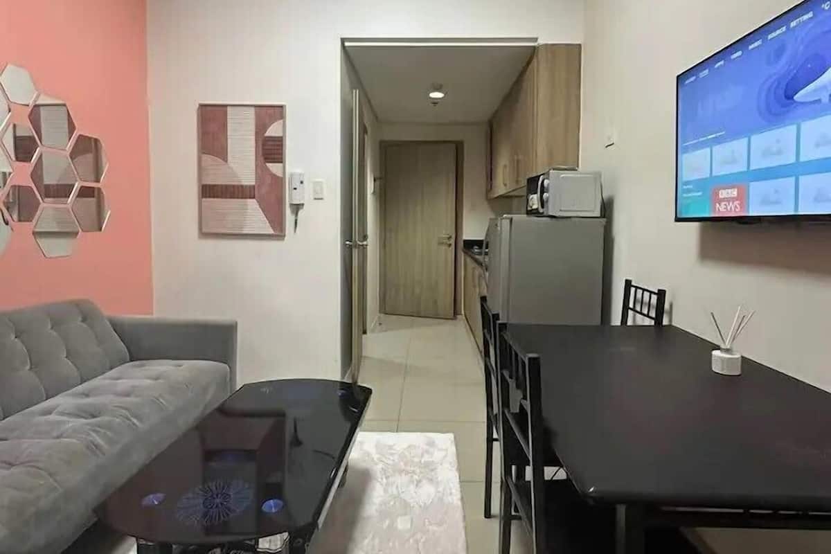 A modern living room with a grey sofa, a black coffee table, and a TV on the wall.