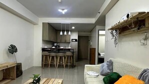 A modern living room with a wooden coffee table, a sofa with colorful cushions, and a kitchen in the background. - House of Wu (Pasay)