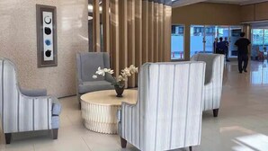 A modern lobby with a round table, two armchairs, a vase with flowers, and a decorative wall piece. - House of Wu (Pasay)