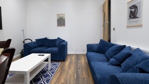 Ein modernes Wohnzimmer mit zwei blauen Sofas, einem weißen Couchtisch und einem gemusterten Teppich.