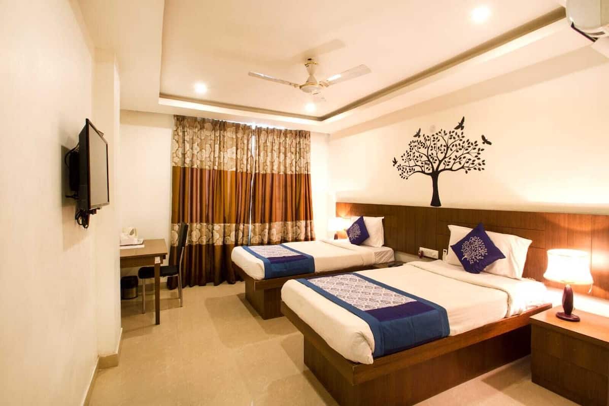 A hotel room with two beds, a desk, a TV, and a ceiling fan.