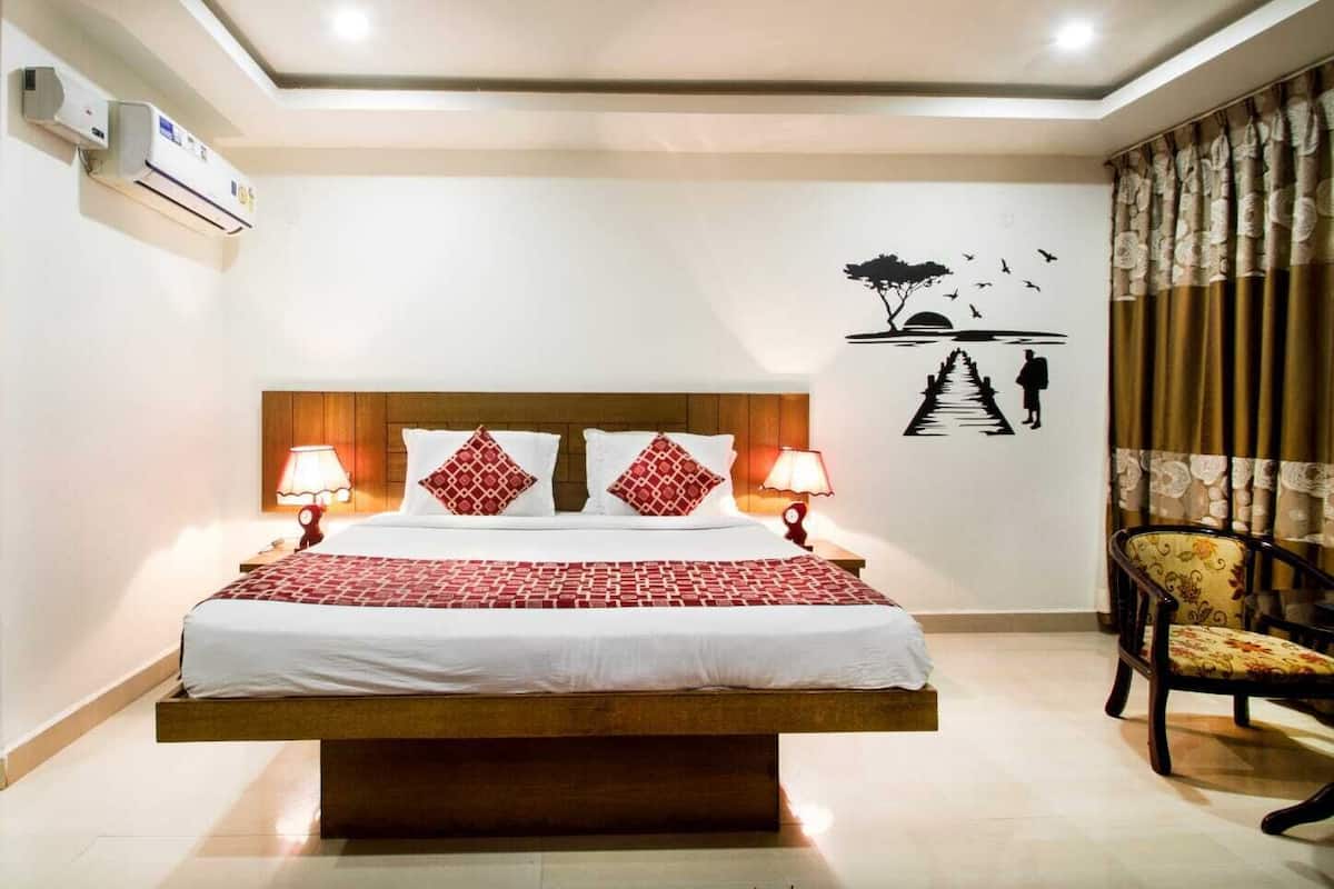 A hotel room with a wooden bed, two bedside lamps, a wall mural, and a chair.