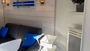 A modern living room with a grey sofa, blue cushions, a white coffee table, and a wall-mounted surfboard decoration.