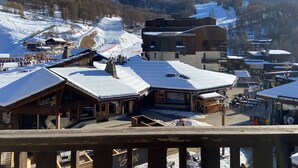 A ski resort with wooden buildings, a ski lift, and snow-covered mountains in the background.