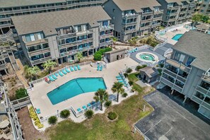 A multi-story hotel with a central swimming pool, outdoor seating, and a parking area. - Shipwatch I Unit 234 - Ocean Nearby (Myrtle Beach)
