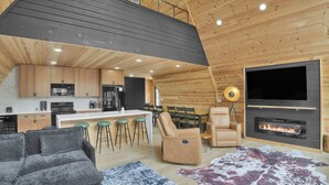 L’intérieur d’une maison en rondins moderne, comprenant une cuisine, un coin repas et un salon.