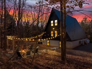 Cozy cabin nestled in a forest, offering a fire pit and outdoor seating area.