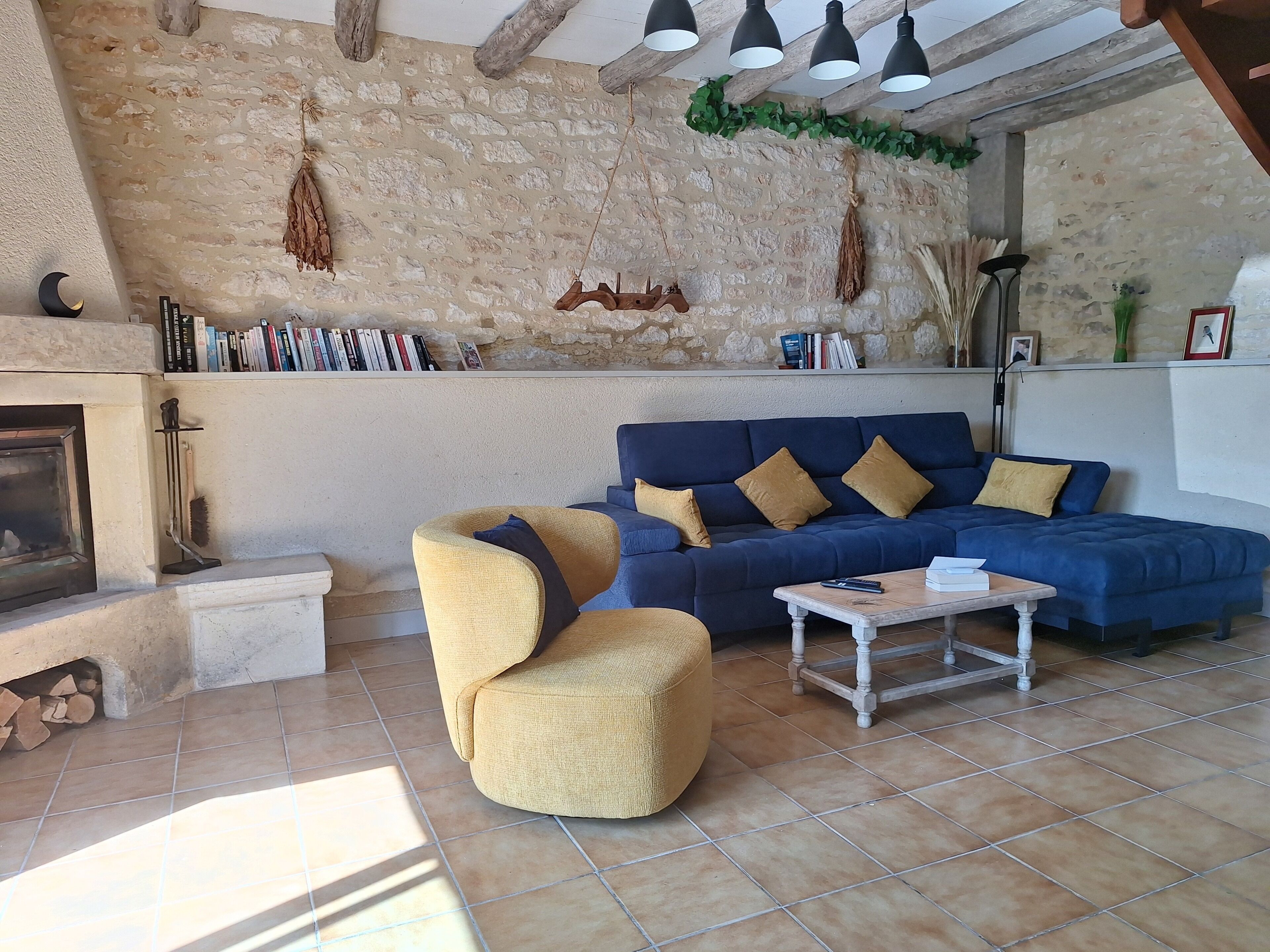 Ein Wohnzimmer mit Steinwand, einem blauen Sofa, einem gelben Sessel und einem Kamin.