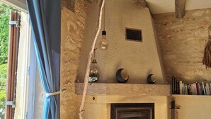 A rustic interior with a stone fireplace, wooden beams, and a bookshelf.