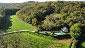 A rural landscape with a house surrounded by lush greenery and a winding road.