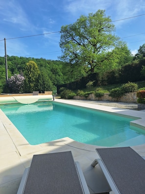 A rectangular swimming pool with a tiled deck, surrounded by greenery and trees. - A little piece of paradise for an unforgettable stay: dining, tourism, relaxation... (Salignac-Eyvigues)