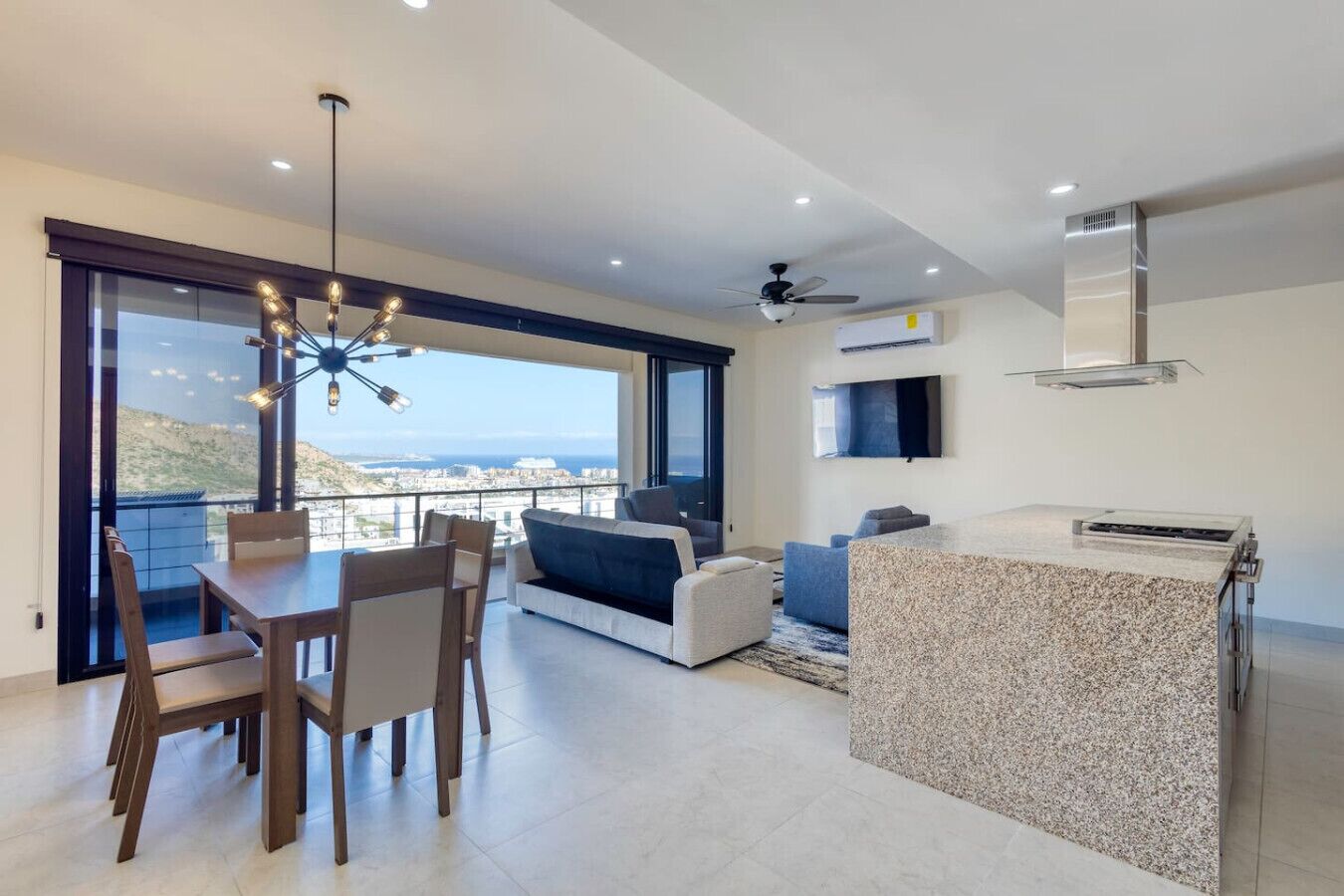 A modern living room with a dining area, a kitchen island, and a large window offering a city view.