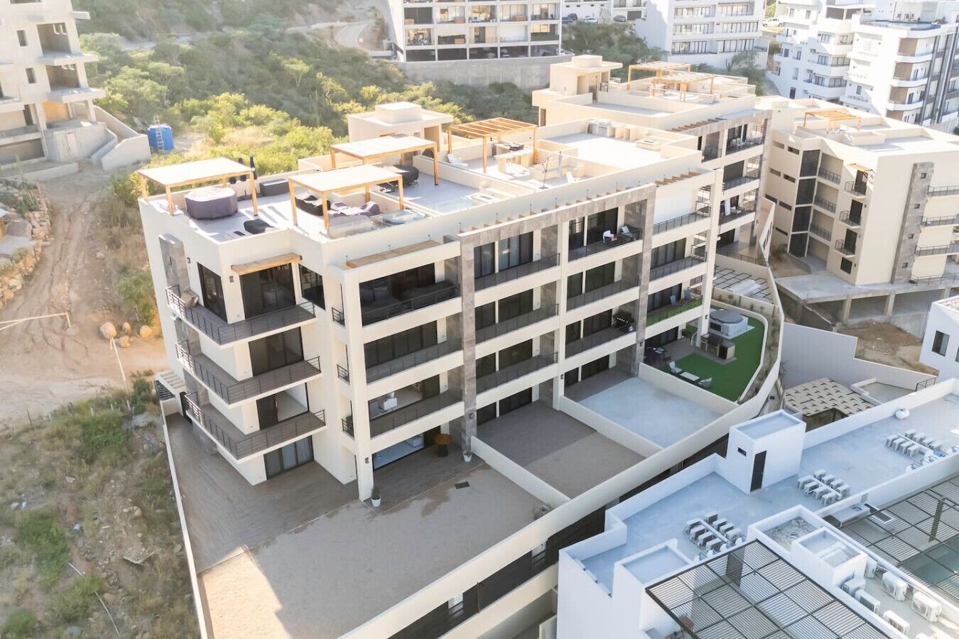 Un immeuble résidentiel à plusieurs étages, doté de balcons, d’une terrasse sur le toit et d’une petite cour intérieure.