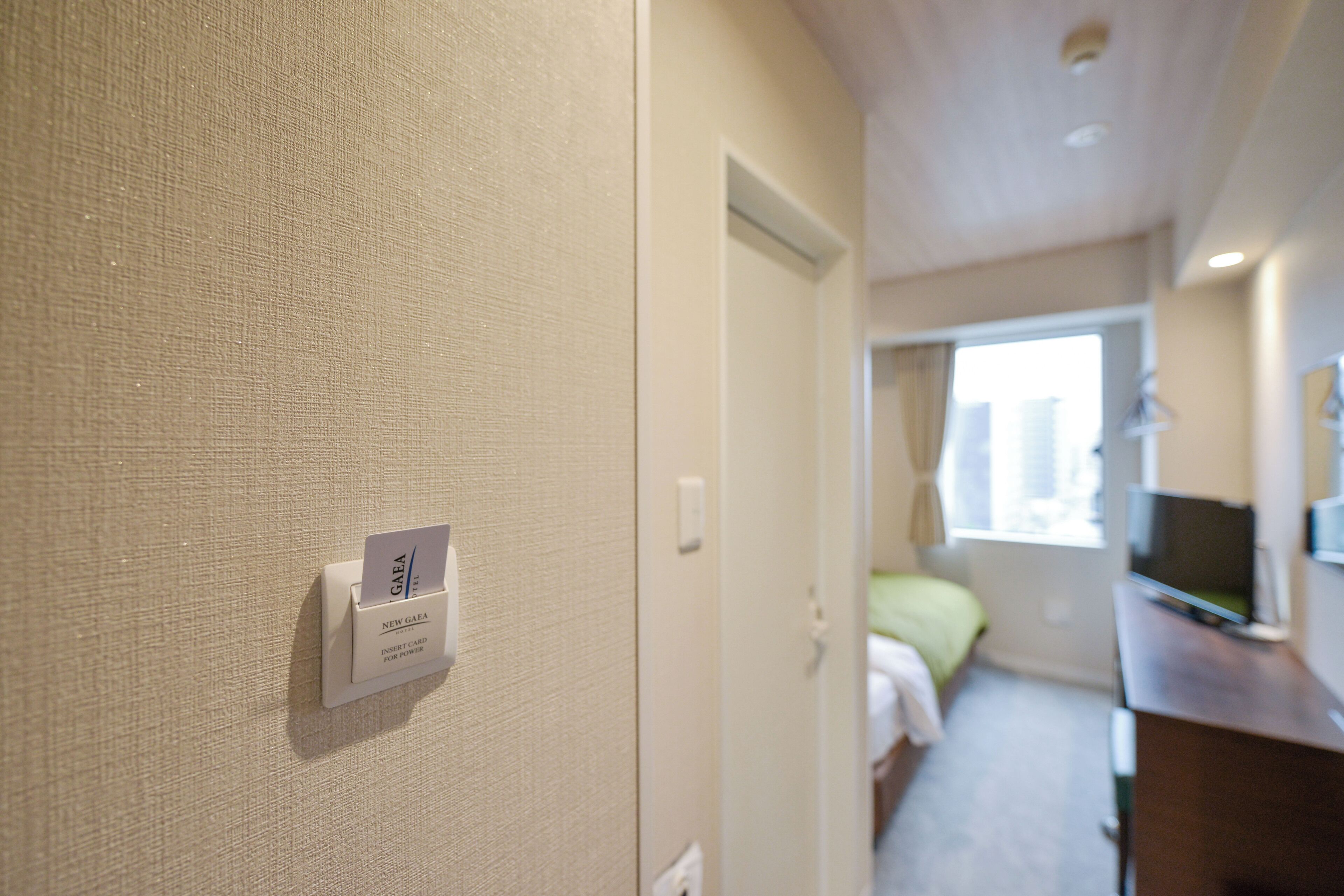 Een hotelkamer met een bed, een bureau, een televisie en een kaartlezer op de muur.