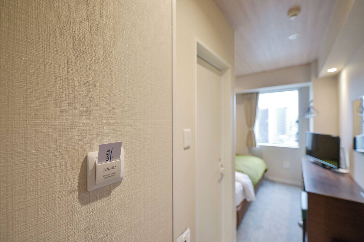 Una habitación de hotel con cama, escritorio, televisor y un lector de tarjetas en la pared.