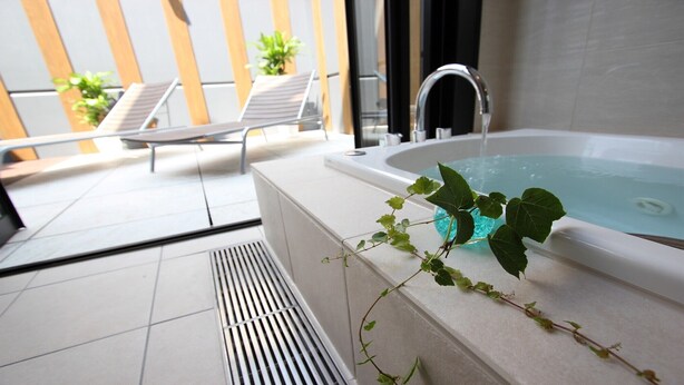 A modern indoor pool area with a hot tub, lounge chairs, and a potted plant.