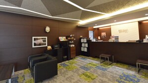 A hotel reception area with a modern design, including a reception desk, seating area, and a clock on the wall.
