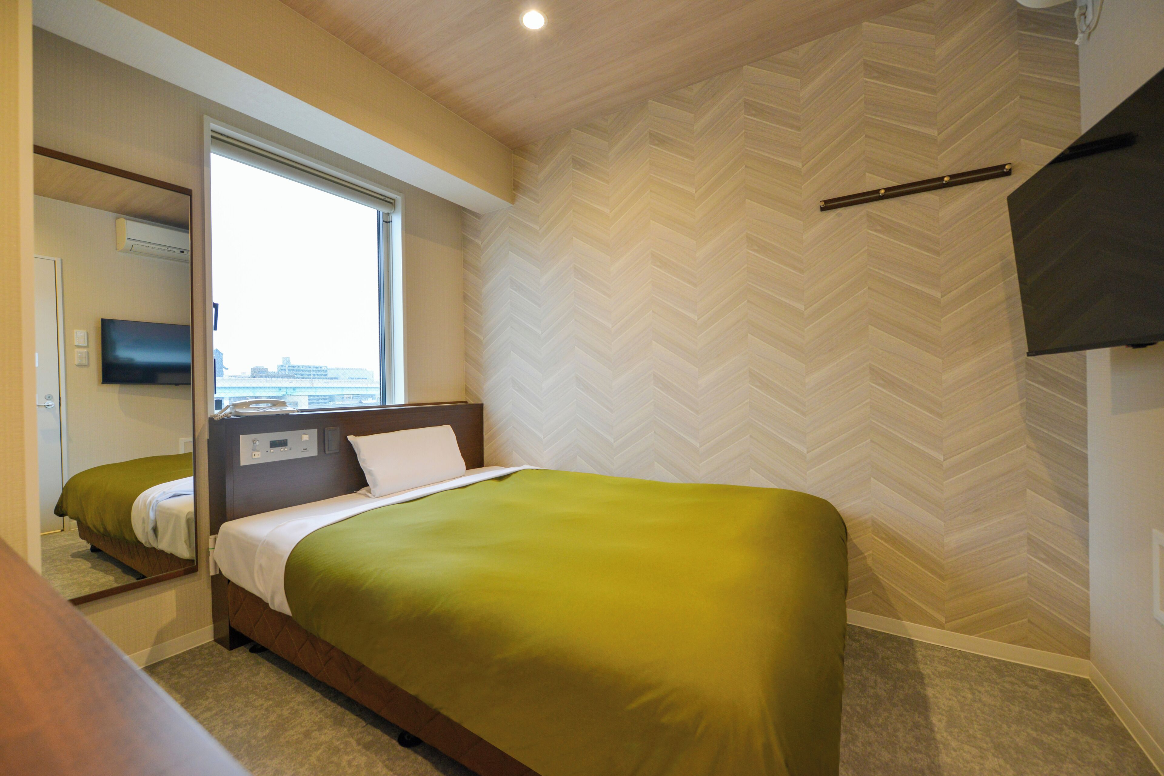 Een hotelkamer met een bed, een televisie en een raam met uitzicht.