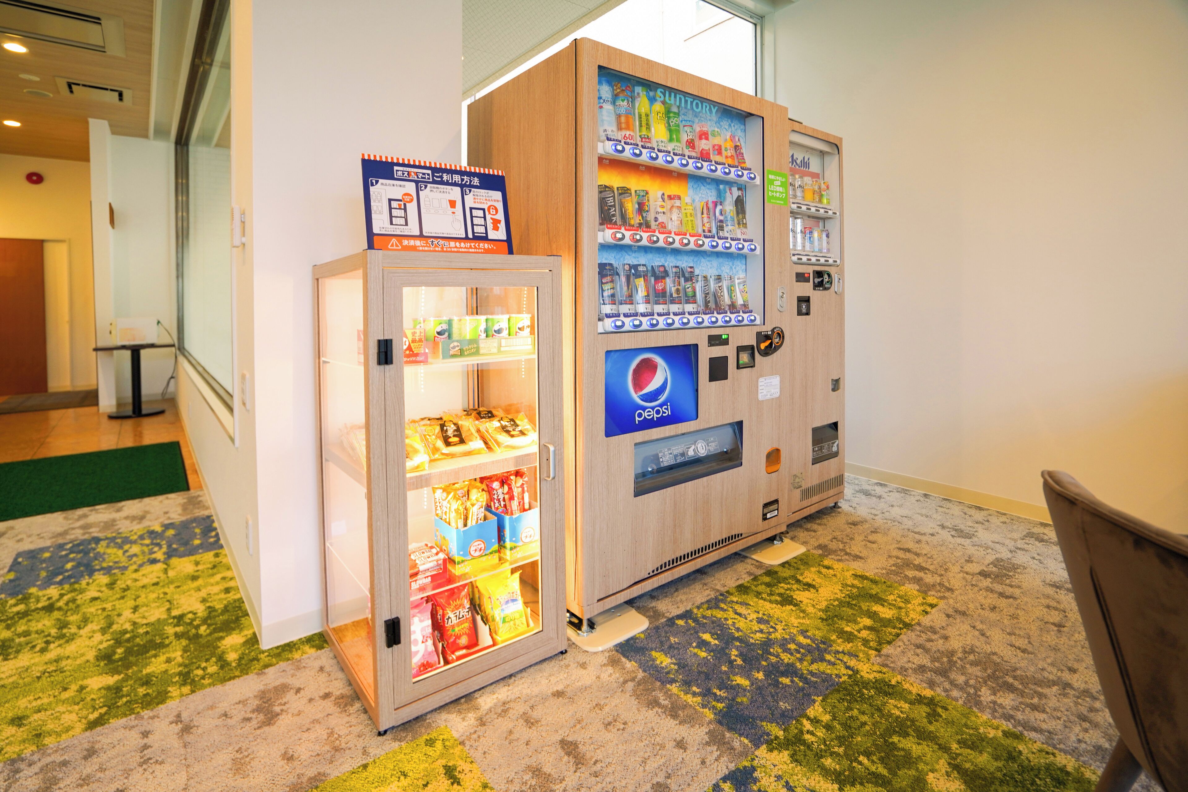 Máquina automática com o logotipo da Pepsi e uma geladeira com vidro, abastecida com lanches.