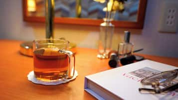 A glass of tea on a wooden table, a book, and a pair of glasses.