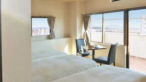 Een hotelkamer met twee bedden, een klein tafeltje met een stoel, en een raam met gordijnen.