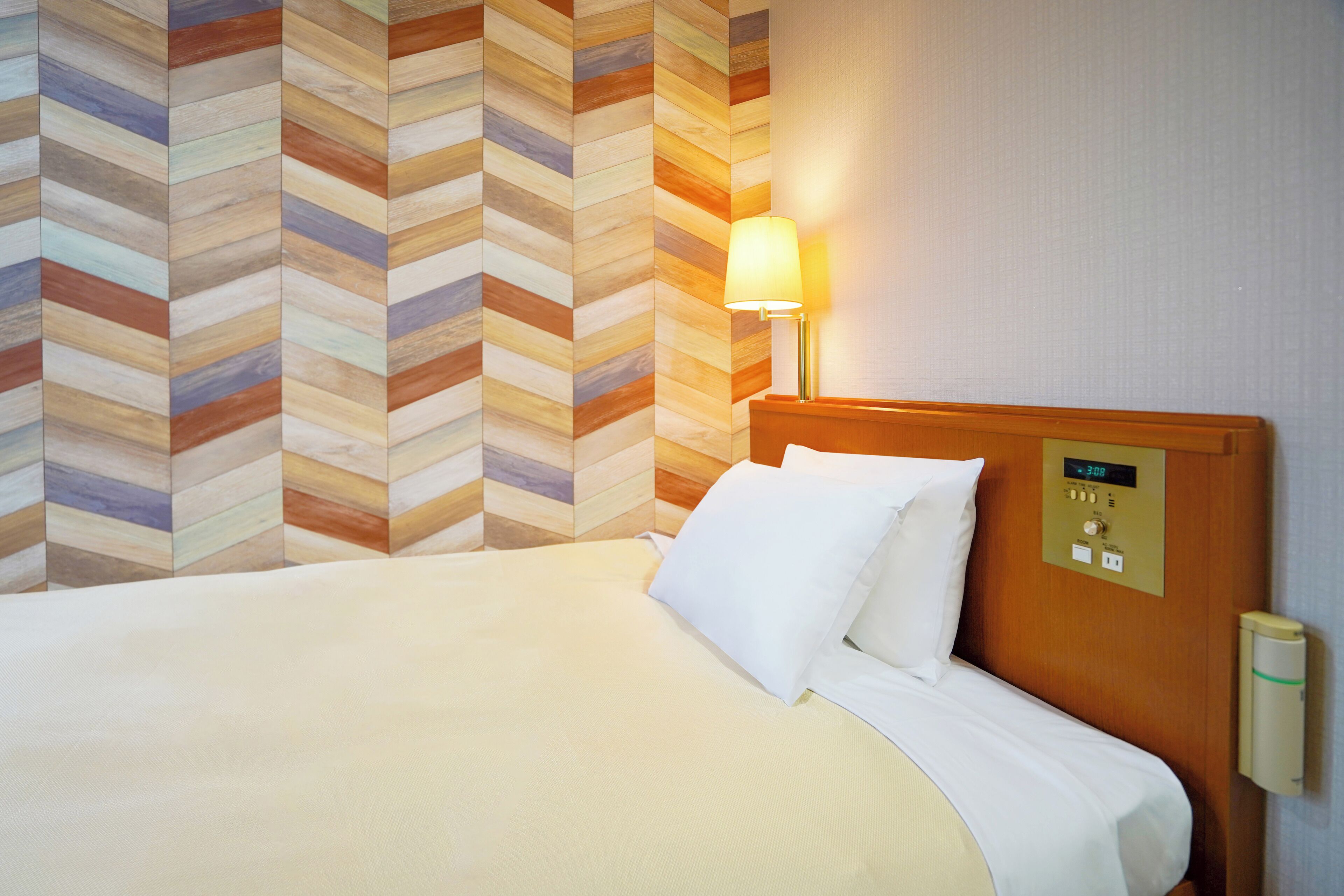 Una habitación de hotel con una cama grande, un cabecero de madera, un reloj de pared y una lámpara de pared.