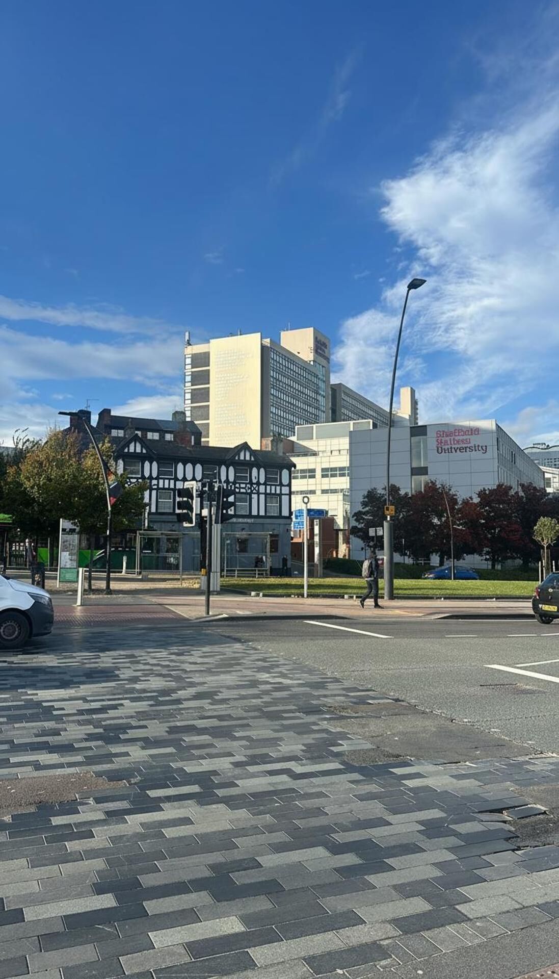 Una intersección urbana con un edificio universitario, una construcción tradicional y un rascacielos moderno.