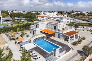 A modern villa with a swimming pool, outdoor seating, and a view of the surrounding neighborhood. - Villa Alegria (Porches)