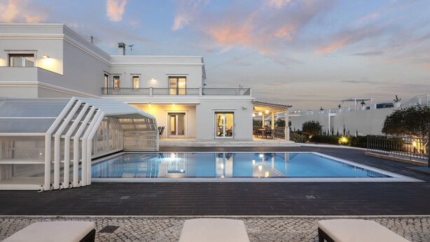 Una casa moderna con piscina, mobiliario exterior y una zona de patio bien iluminada.