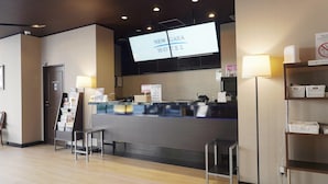 A reception desk with a digital screen displaying "NEW CAEA HOTEL" and a sign with a no-smoking symbol. - Hotel New Gaea Yakuin (Fukuoka)