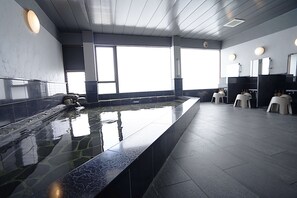 Un área de piscina interior moderna con una piscina larga y rectangular, baldosas de piedra y un diseño limpio y minimalista.